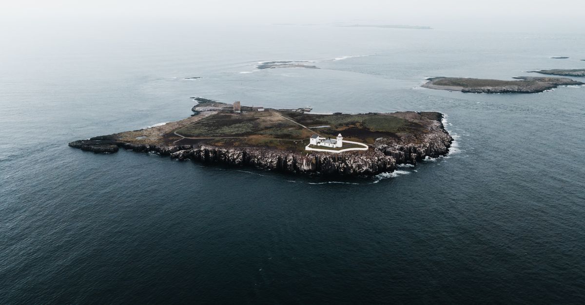 Stunning aerial shot of the isolated Farne Islands and lighthouse in Northumberland, UK.