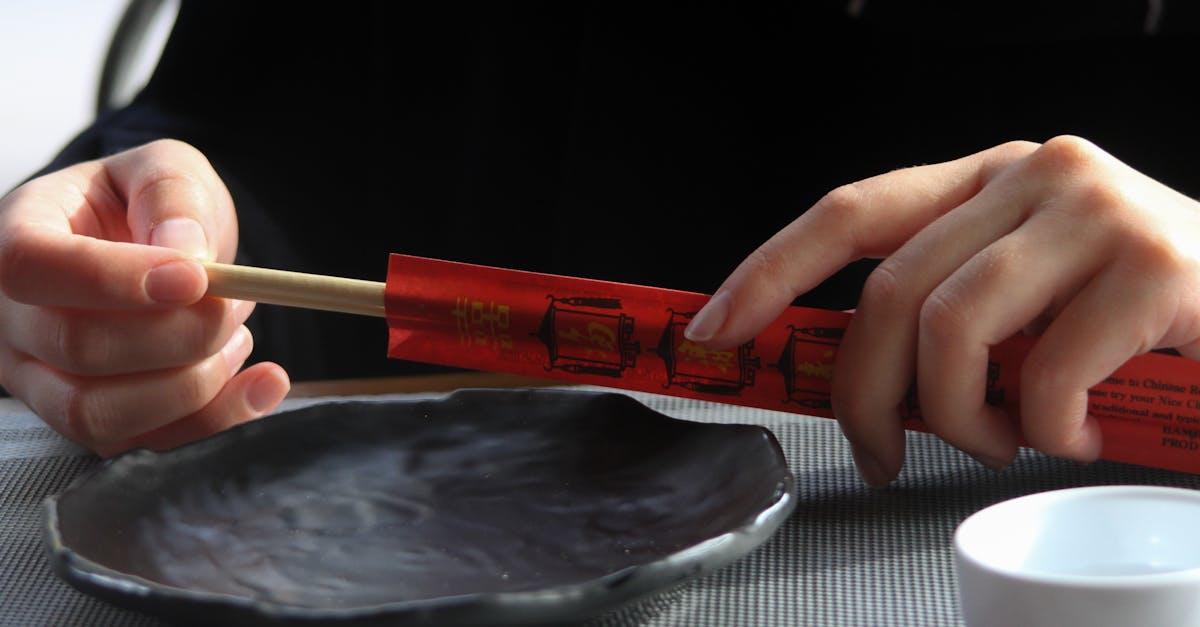 Close-up shot of hands holding chopsticks over an empty plate, perfect for Asian cuisine themes.