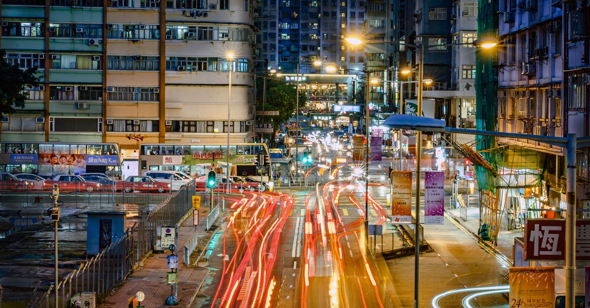Vibrant Hong Kong street scene with light trails and city lights at night, showcasing busy urban life.
