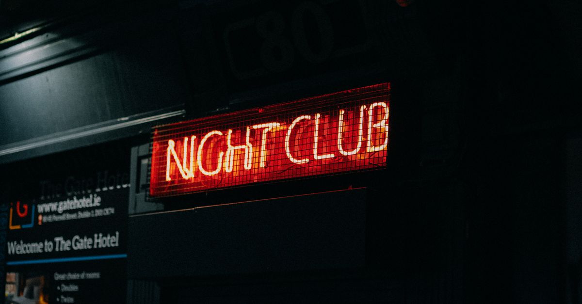 Close-up of a neon-lit 'Night Club' sign in a dark urban setting capturing nightlife ambiance.