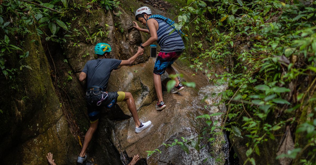 Group of adventurers scaling a rocky path amidst lush greenery in Peru, displaying teamwork and determination.