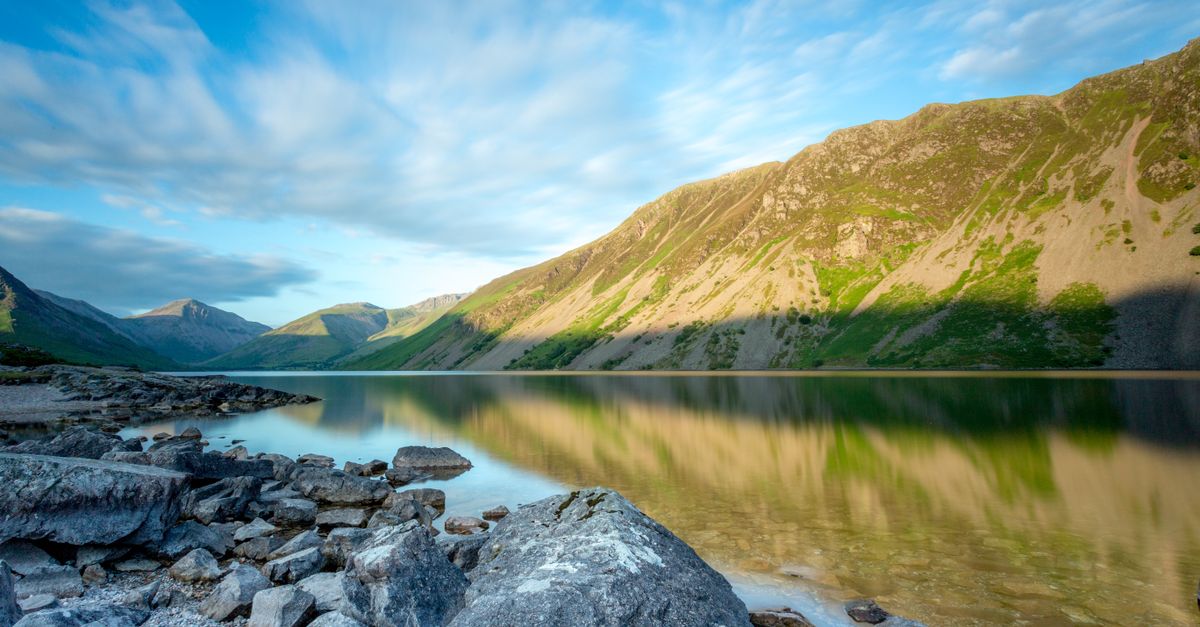 Beautiful landscape of a serene lake reflecting mountains and sky in England's countryside, ideal for travel and nature enthusiasts.