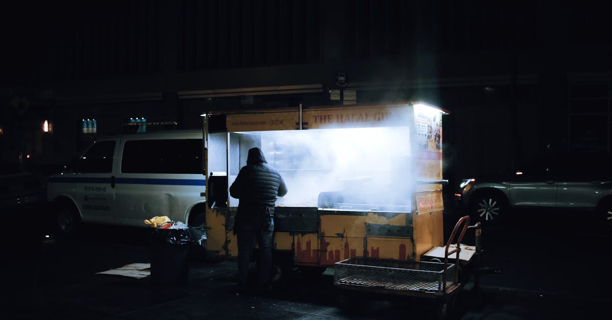 A street vendor prepares food at a night market with illuminated smoke.