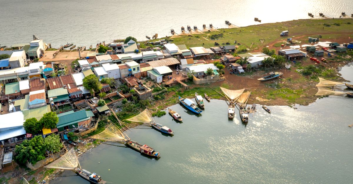Scenic aerial view of a fishing village by the sea with boats and nets at sunset.