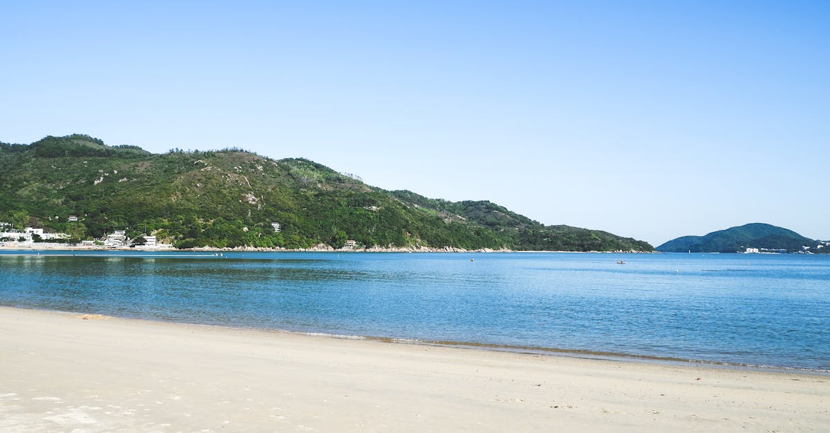 Tranquil beach scene on Lamma Island, Hong Kong with clear blue skies and lush greenery.