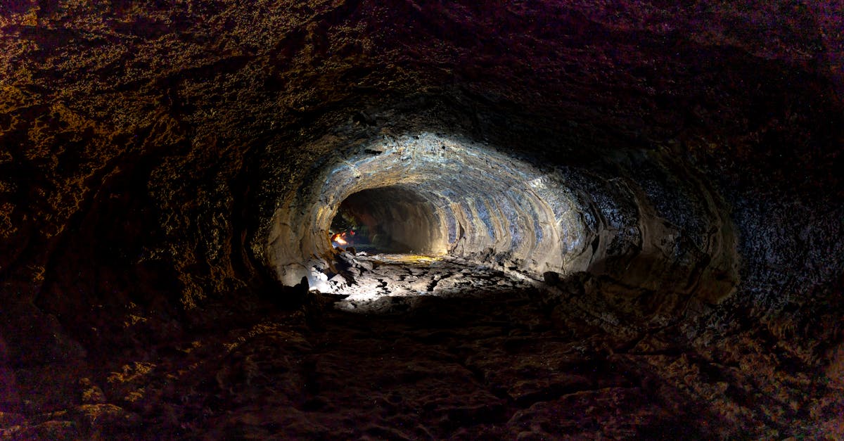 Explore the depths of a cave tunnel with dramatic lighting and intricate textures.