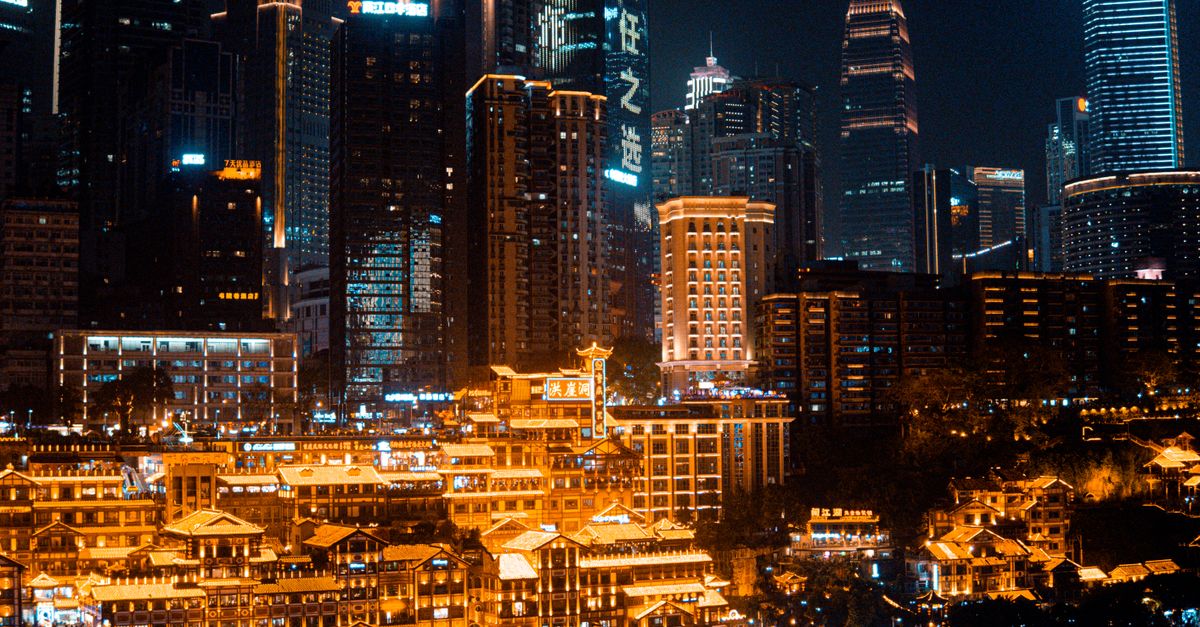 Illuminated view of Hongyadong in Chongqing cityscape at night showcasing traditional Chinese architecture and modern skyscrapers.