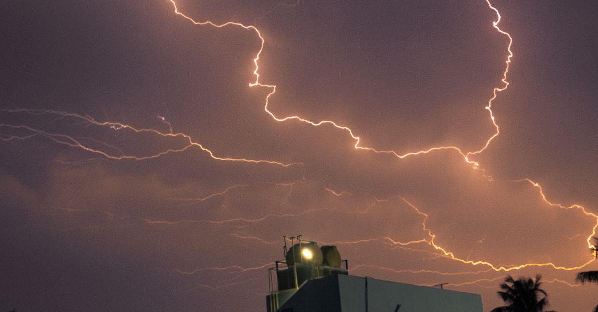 Captivating night view of a powerful lightning storm illuminating the sky above a building.