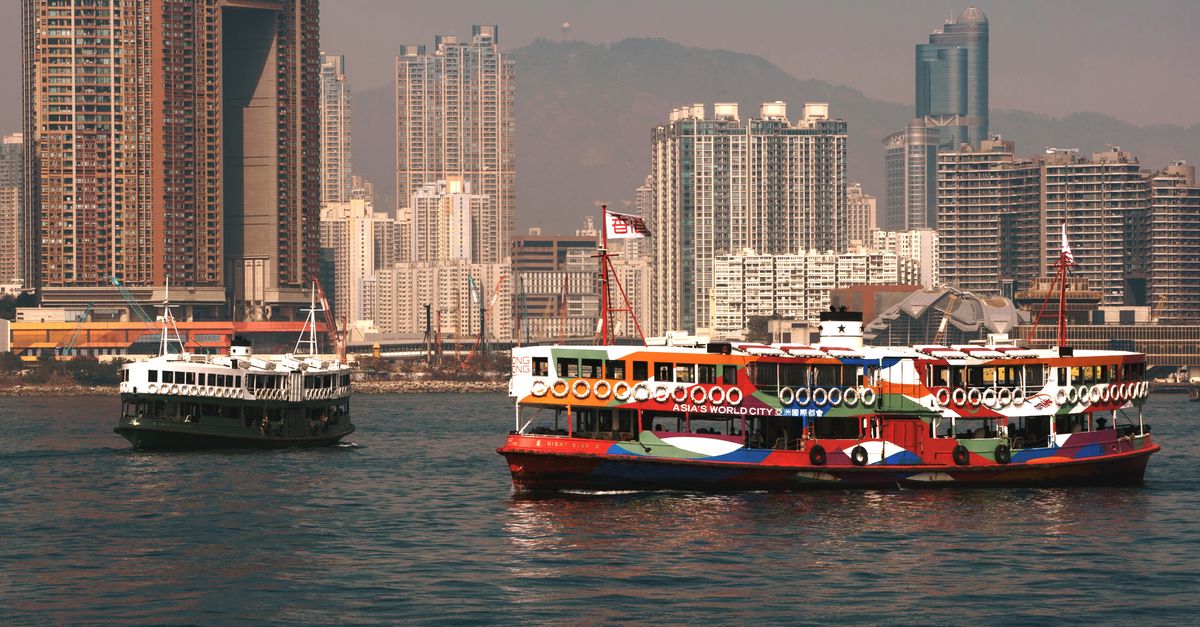 A vibrant ferry sails through Victoria Harbour with Hong Kong skyscrapers in the background.