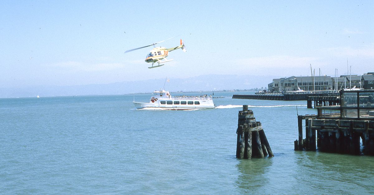 Helicopter flying over a bay with a boat nearby on a sunny day, perfect for travel imagery.