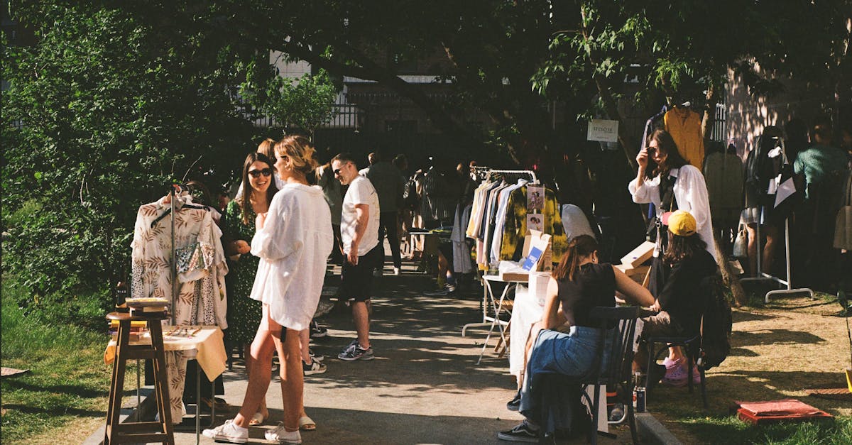 Vibrant street market scene with people shopping for clothes on a sunny day.