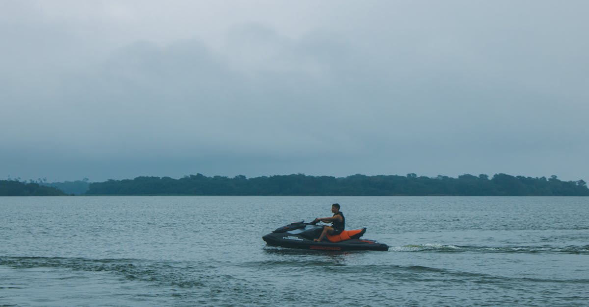 A person enjoys a peaceful jet ski ride on a tranquil sea under overcast skies.