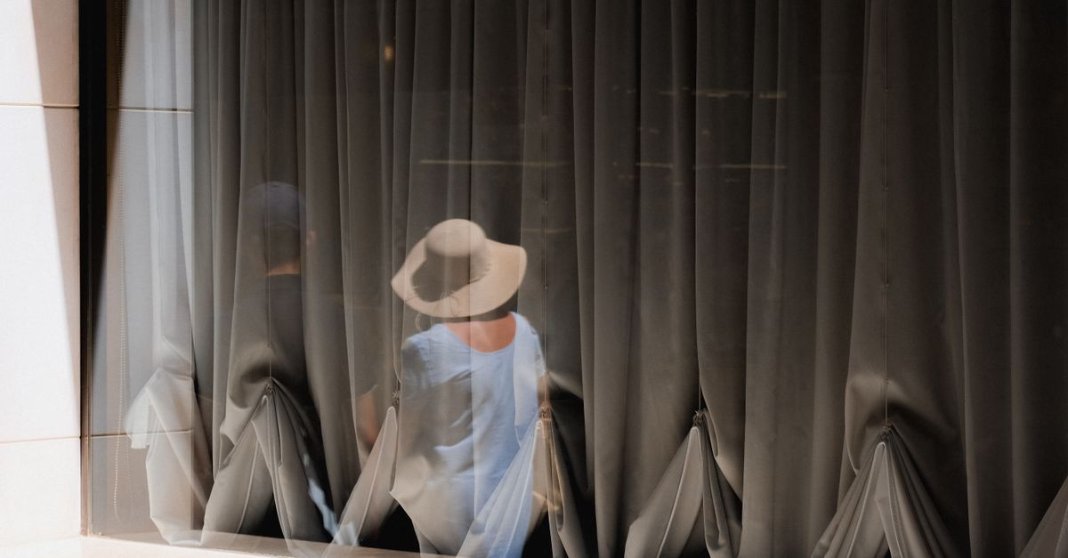 Two people seen as reflections through semi-transparent curtains, capturing a mysterious and intriguing scene.
