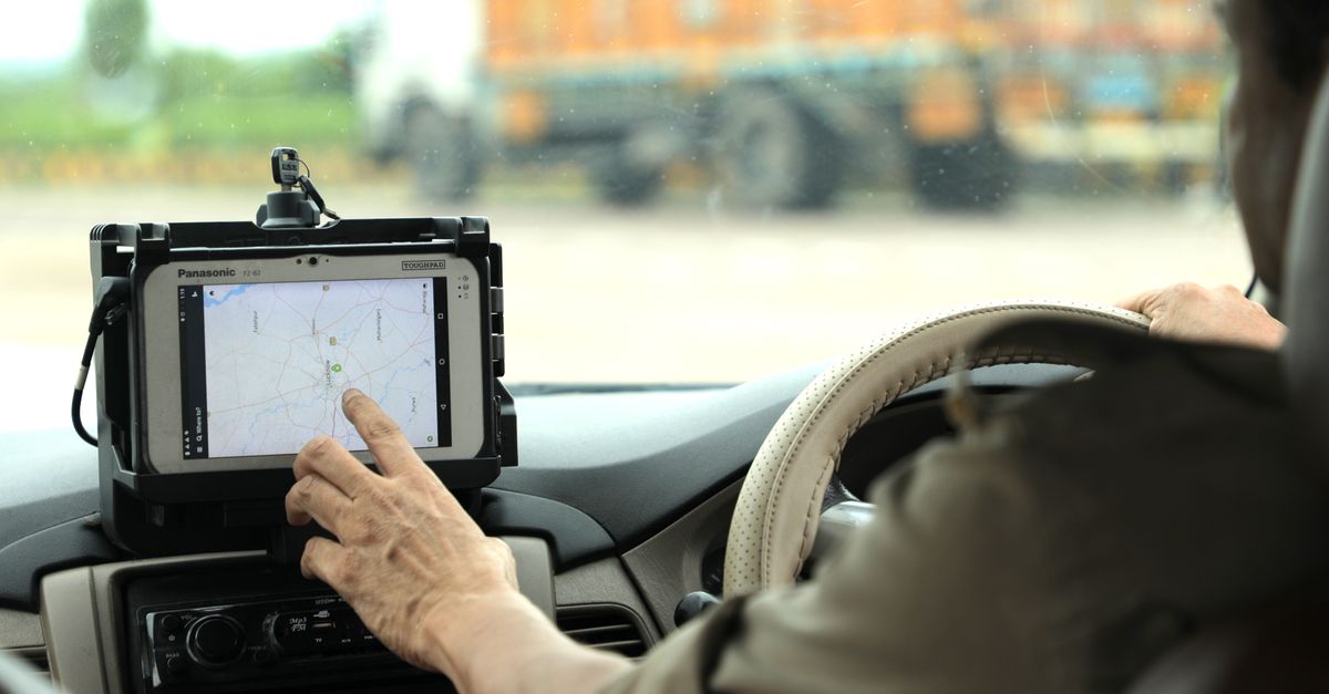 Police officer navigates using a digital map on a tablet inside a vehicle.