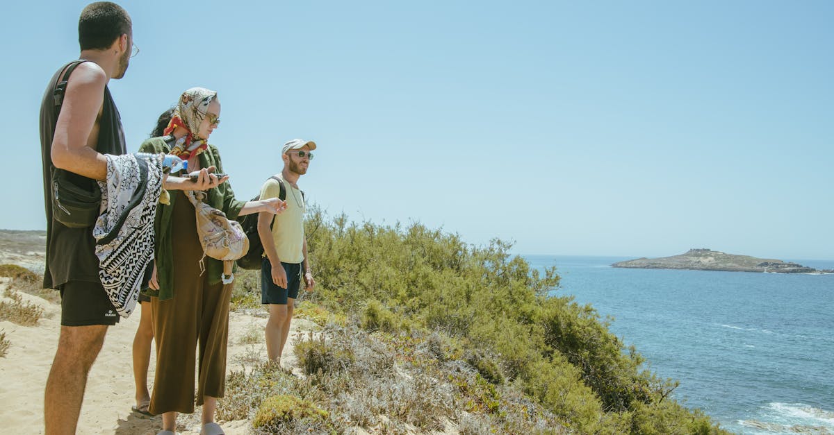 A group of adults enjoys a sunny day adventure near the ocean on coastal cliffs.