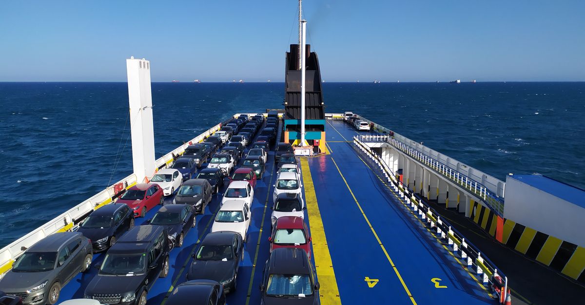 A sea ferry carrying cars across the ocean on a clear day, depicting maritime travel.
