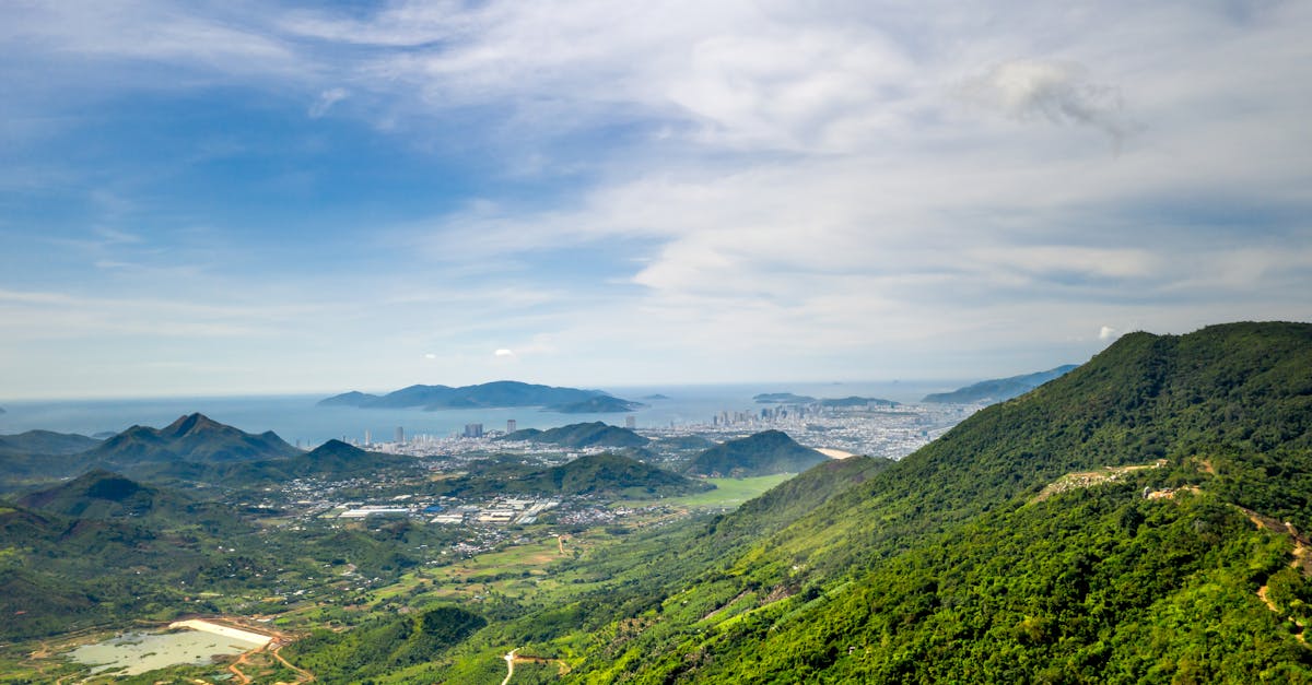 Breathtaking aerial view of a lush green mountain landscape with a coastal city in the background.
