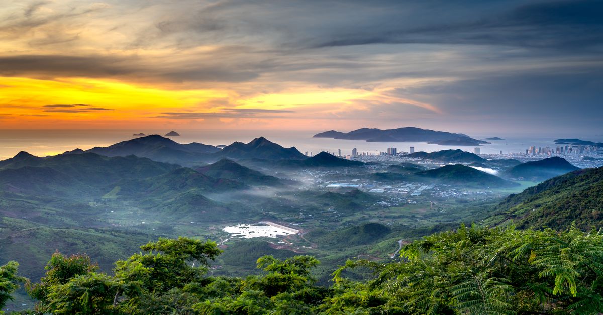Breathtaking view of mountain range and cityscape at sunset with colorful sky.