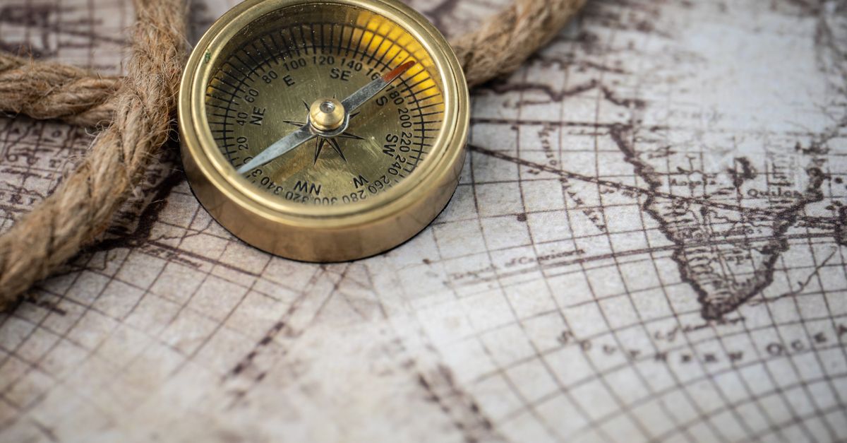 A vintage brass compass rests on an antique map with a nautical rope, evoking exploration and discovery.