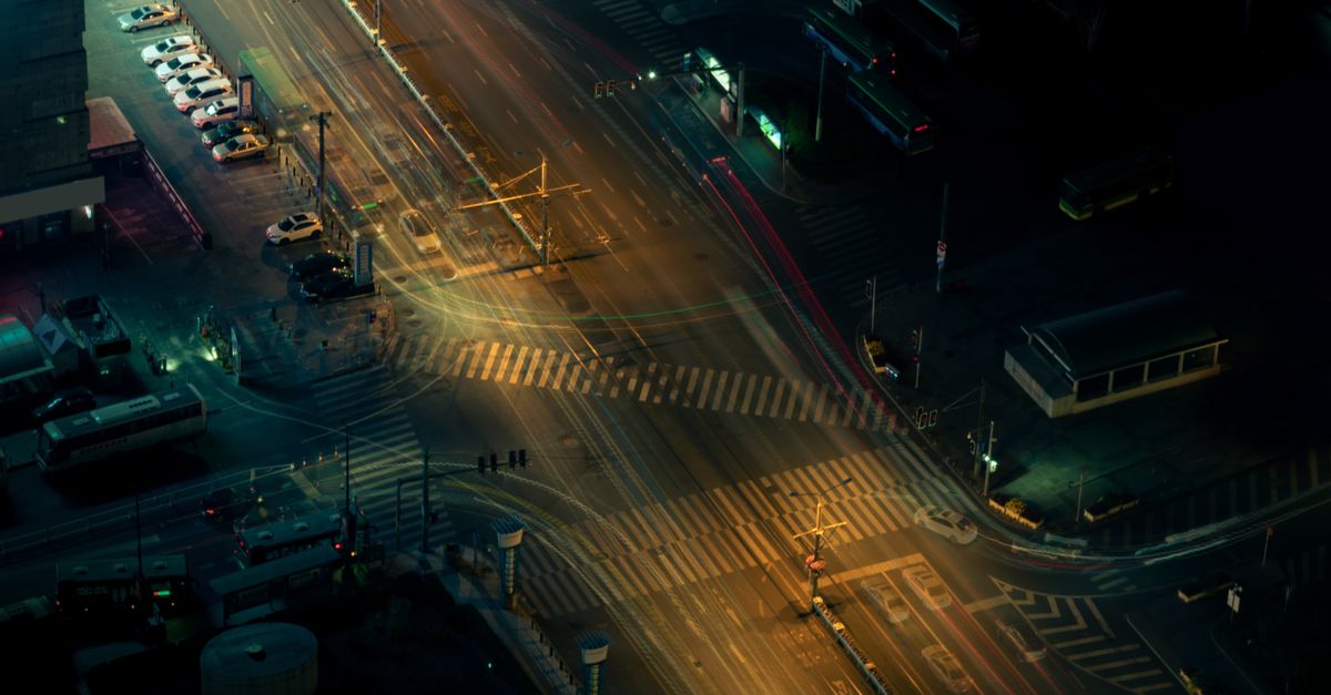 High-angle view of an illuminated urban intersection at night with blurred motion from passing traffic.