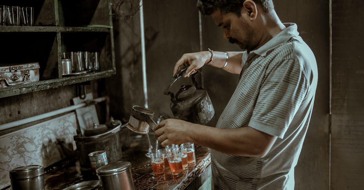 An Indian man pouring tea in a rustic kitchen setting, showcasing a cultural tea-making moment.
