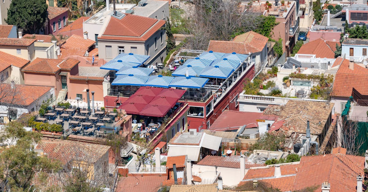 Aerial capture of a sunlit town with traditional rooftops and vibrant umbrellas creating an inviting outdoor space.