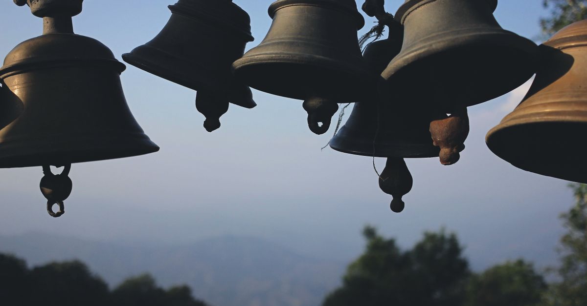 A collection of traditional hanging bells set against a scenic mountain backdrop, showcasing cultural heritage.