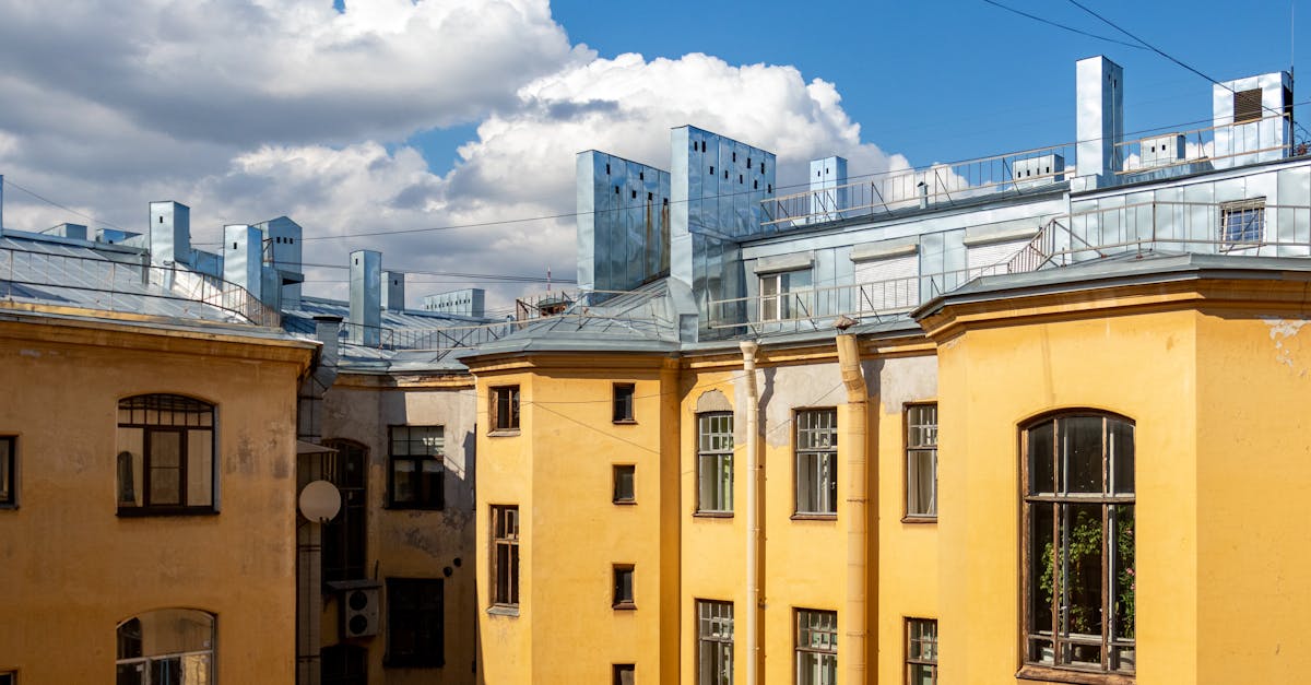 Sunlit vintage buildings with blue sky and clouds, highlighting urban architecture.