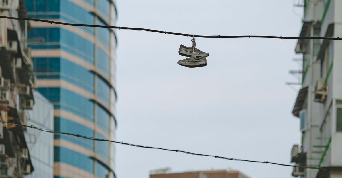 Sneakers hanging on wire amidst Hong Kong skyscrapers, showcasing urban lifestyle and architecture.