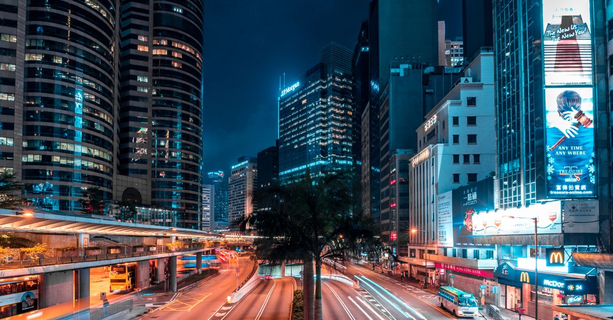 Illuminated urban scene with skyscrapers and busy streets captured at night, featuring dynamic light trails.