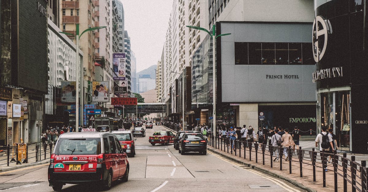 A vibrant city street scene with bustling traffic and busy sidewalks, featuring urban architecture.