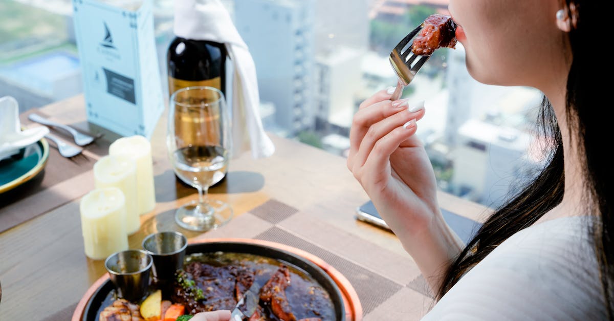 A woman enjoying a fine dining experience with steak and wine in a restaurant setting.