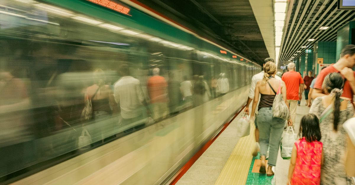 Commuters wait as a subway train passes by, capturing the hustle of urban travel.