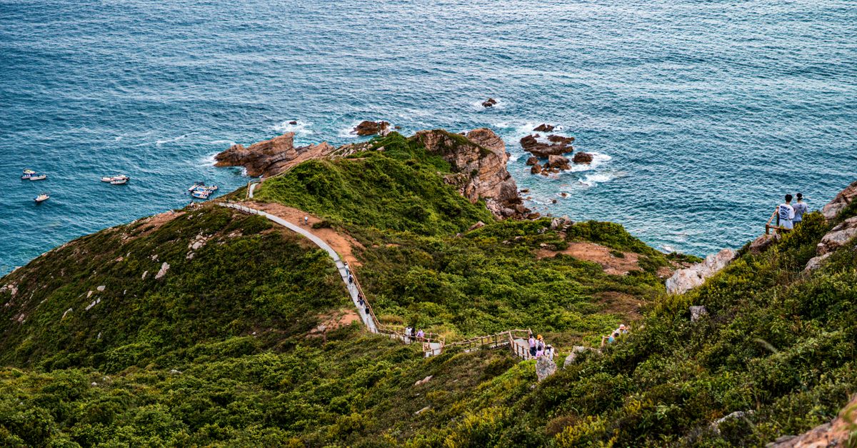 A scenic coastline with a winding path and people enjoying the ocean view.