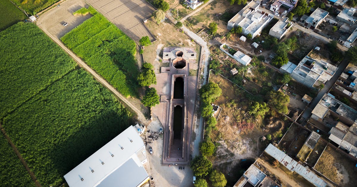 Drone shot of historical construction amidst fields and village in Meham, India.