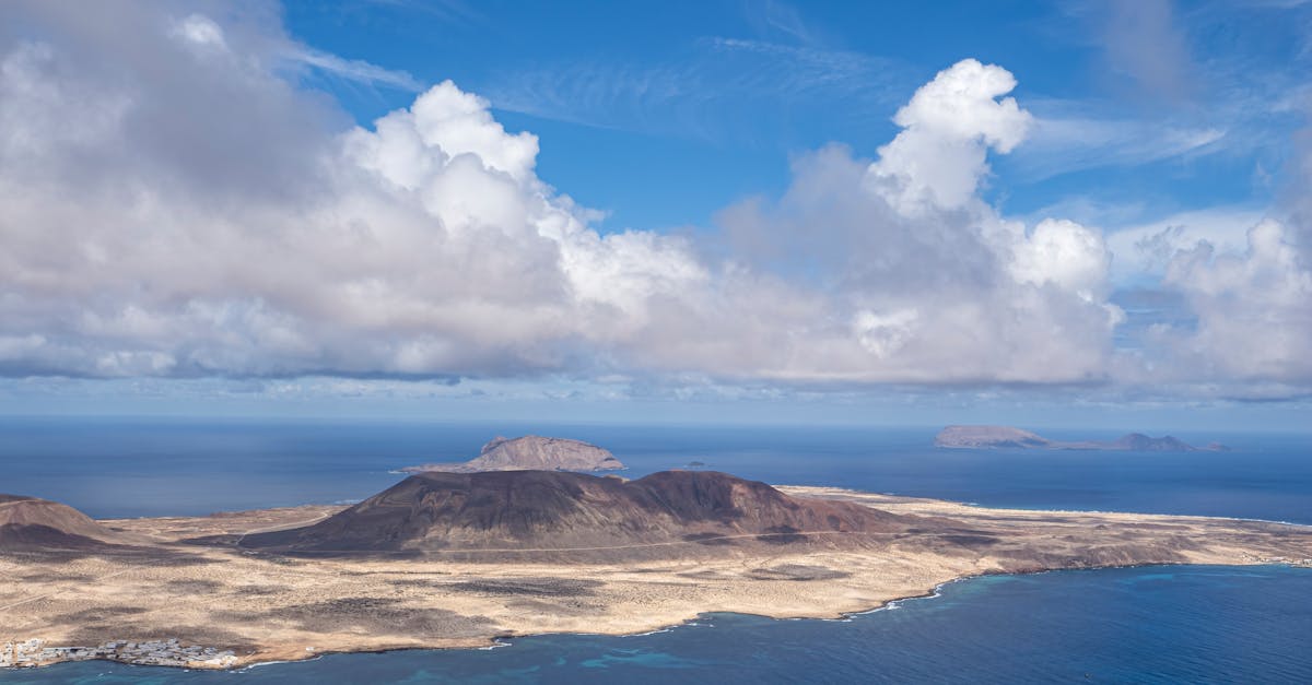 Breathtaking aerial view of Lanzarote's volcanic landscape and ocean under a cloudy sky.
