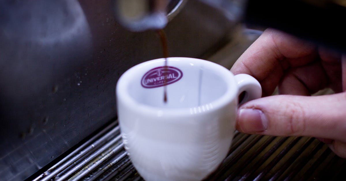 A detailed shot of espresso being poured into a white cup from a coffee machine.