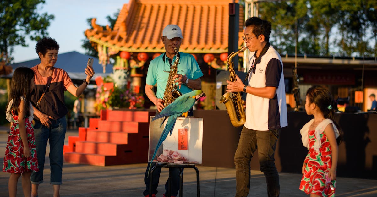 Two saxophonists entertain a family with bright parrots in an urban setting.
