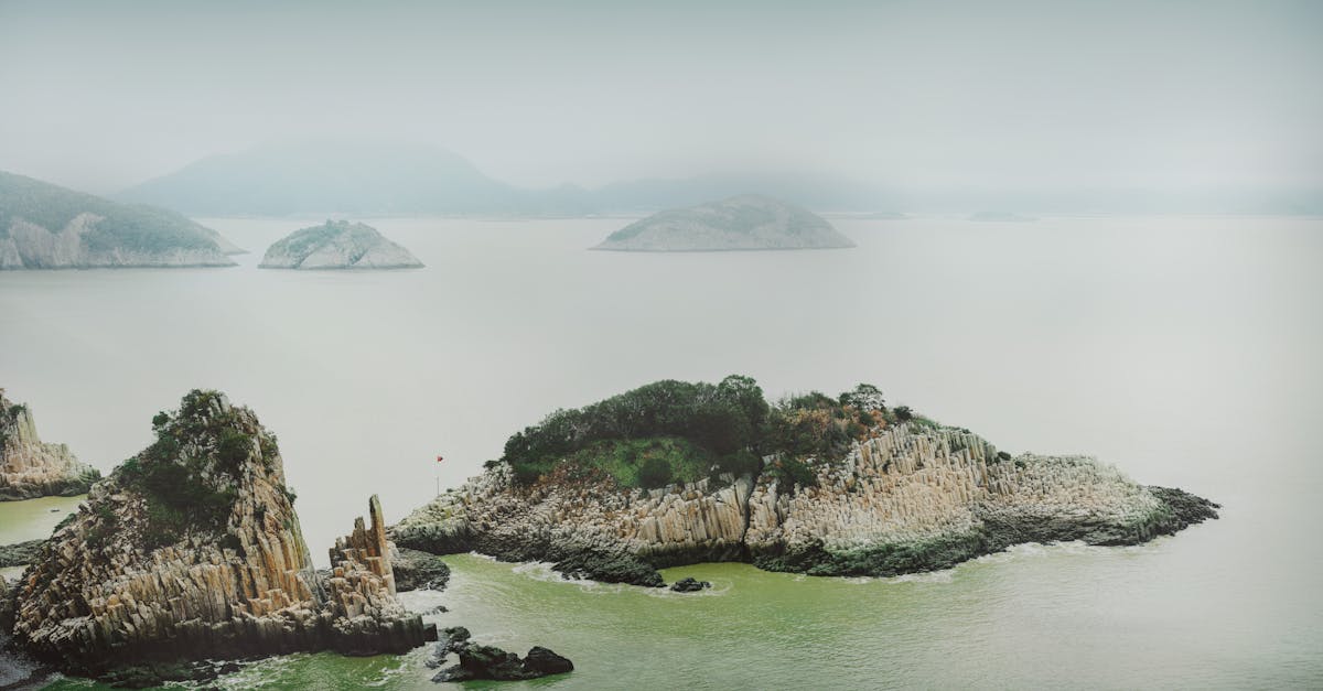 Drone shot of misty coastal islands with unique rock formations and tranquil sea.