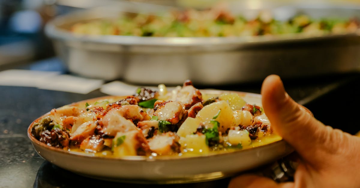 A vibrant dish of octopus and potatoes garnished with herbs, presented on a ceramic plate.