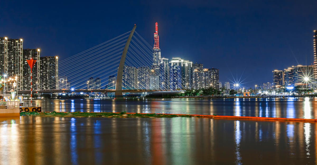 Night view of the illuminated Ba Son Bridge with city skyline in Ho Chi Minh City, Vietnam.