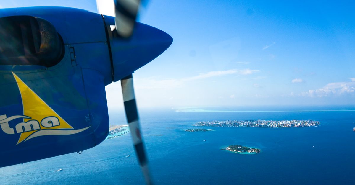 Seaplane flying over the Maldives showcasing clear blue water and lush islands.