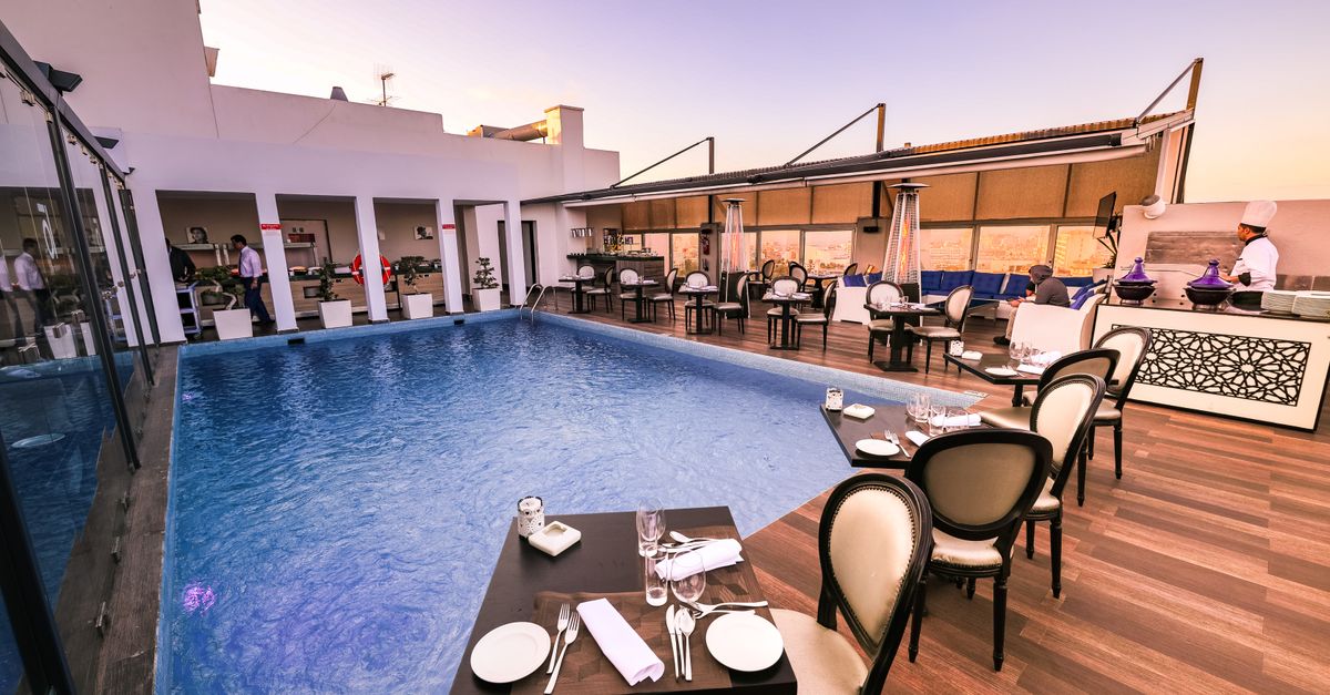 Elegant rooftop dining area with pool and sunset view, perfect for luxury travel and relaxation.