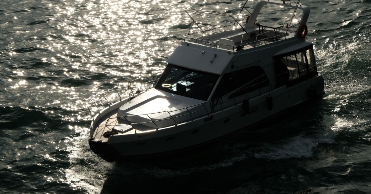A sleek yacht glides effortlessly through sparkling sunlight on open water, creating a serene escape.