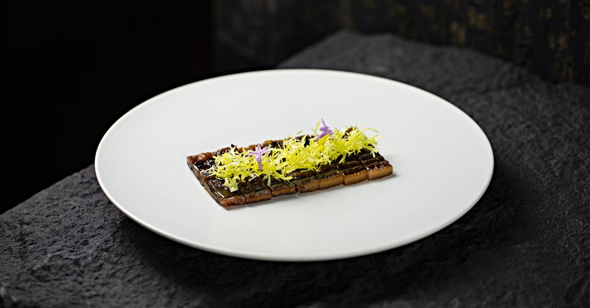 Elegant gourmet dish garnished with edible flowers on a white plate. Perfect for fine dining concepts.