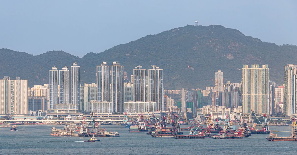 A stunning view of Hong Kong harbor with boats and towering skyscrapers set against a mountainous backdrop.