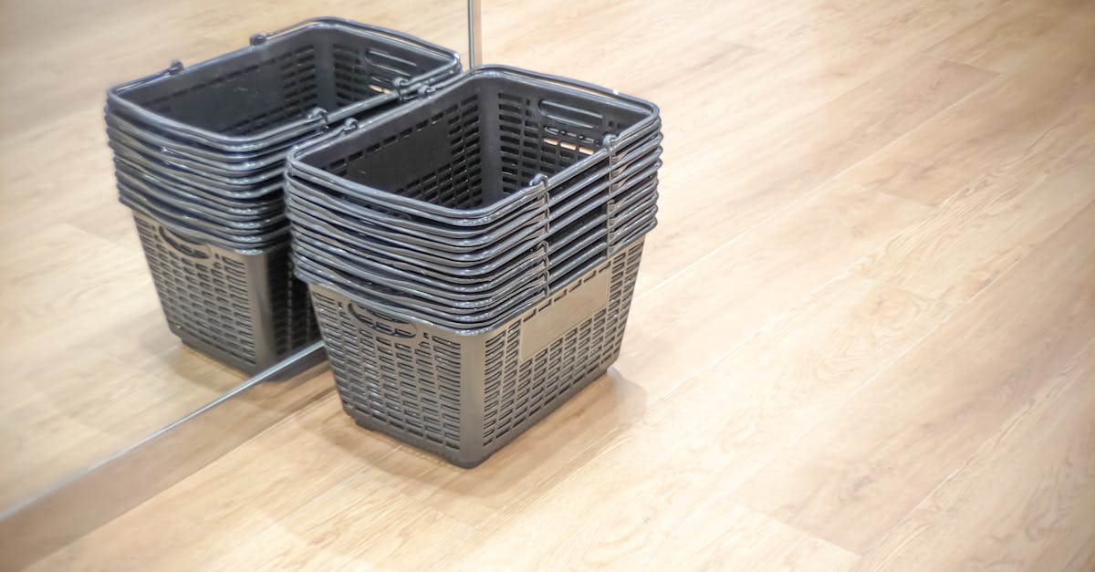 A stack of empty shopping baskets reflected in a mirror on a wooden floor.