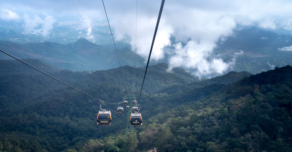Stunning view of cable cars traversing a lush mountain landscape under a cloudy sky.