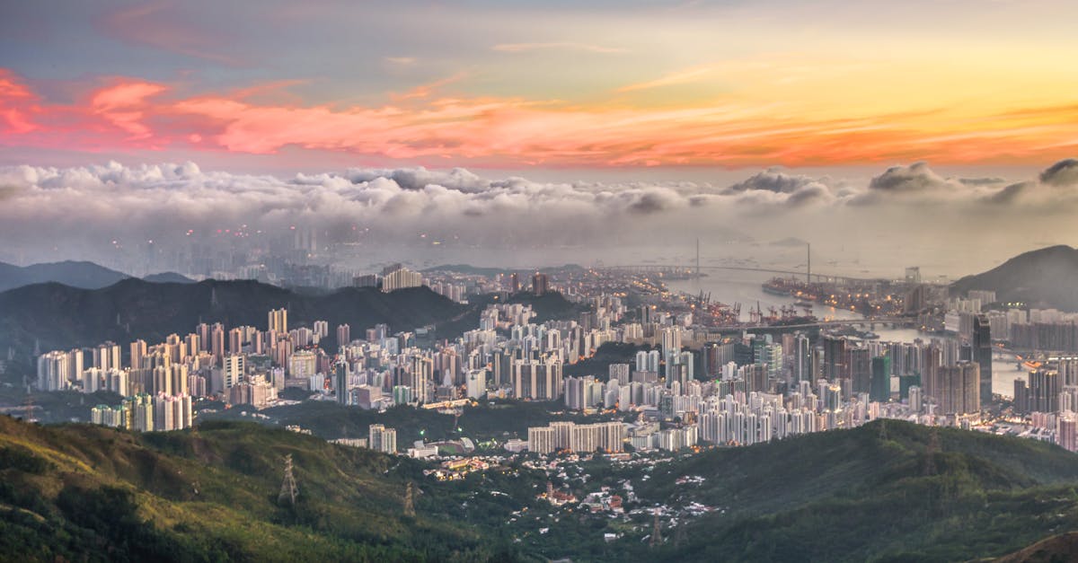 Stunning aerial view of a city's skyline surrounded by mountains and a colorful sunset sky.