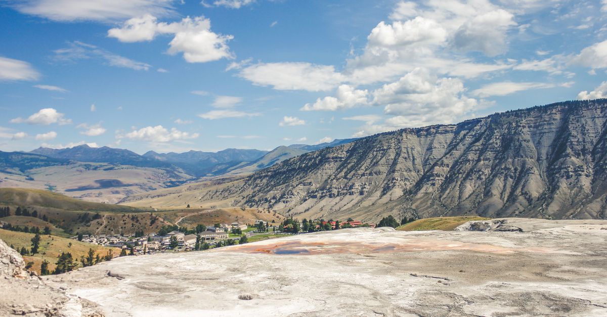 Experience the majestic mountain ranges and scenic hot springs under a clear blue sky.